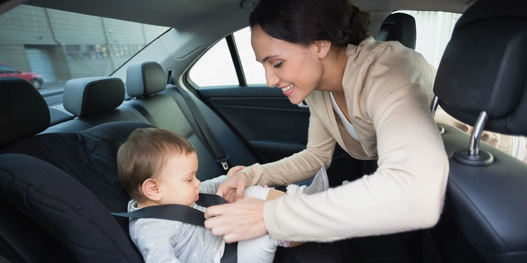 picture of a mom putting the baby in a car seat
