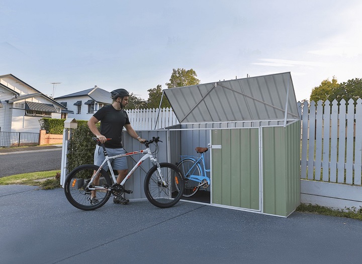 man putting bike into a garden bike shed 