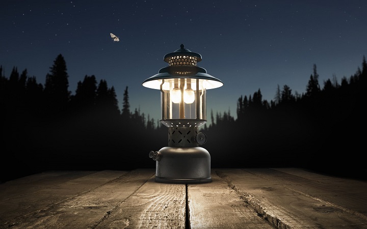 picture of a camping lantern on a wooden table in the woods