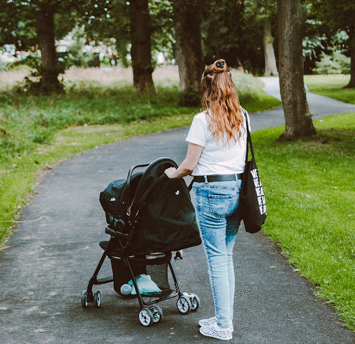 picture of a woman with single stroller walking in a park 