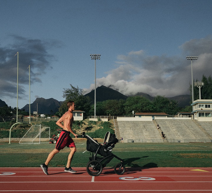 picture of a men jogging with a stroller on a field 