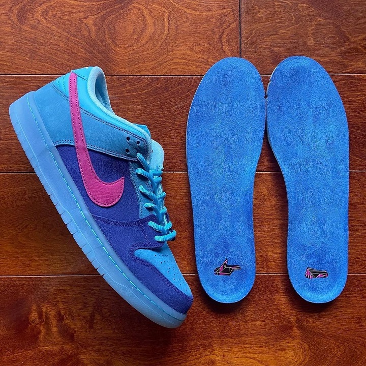 blue nike sb dunk sneaker and two blue insoles placed on a laminate floor